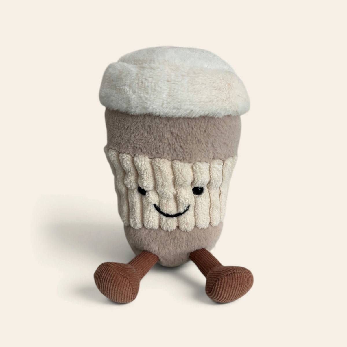 Amuseables Coffee-to-Go A6COF: a plush takeaway coffee cup toy with a fluffy white lid, a beige ribbed sleeve, a smiling face and brown corduroy legs