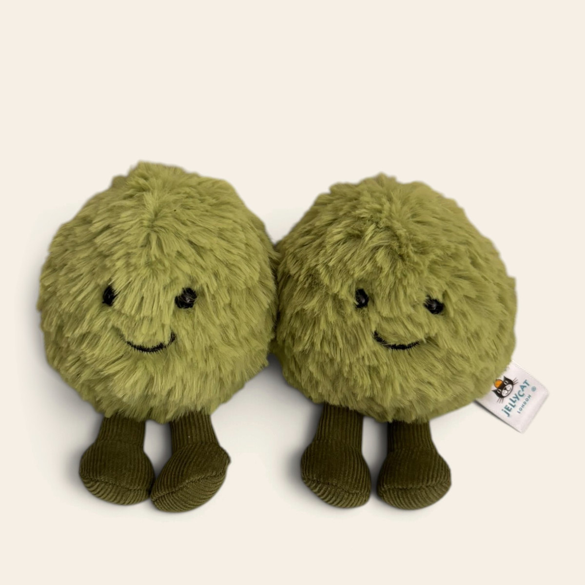 Dot and Peg Mushy Peas A6MSP: two round fluffy green plush peas side by side, with smiling faces and dark green corduroy legs