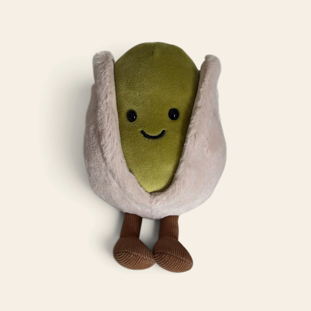 Amuseables Horatio Pistachio A6PST: a plush pistachio toy with a beige fuzzy shell, a green nut, a smiling face and brown corduroy legs