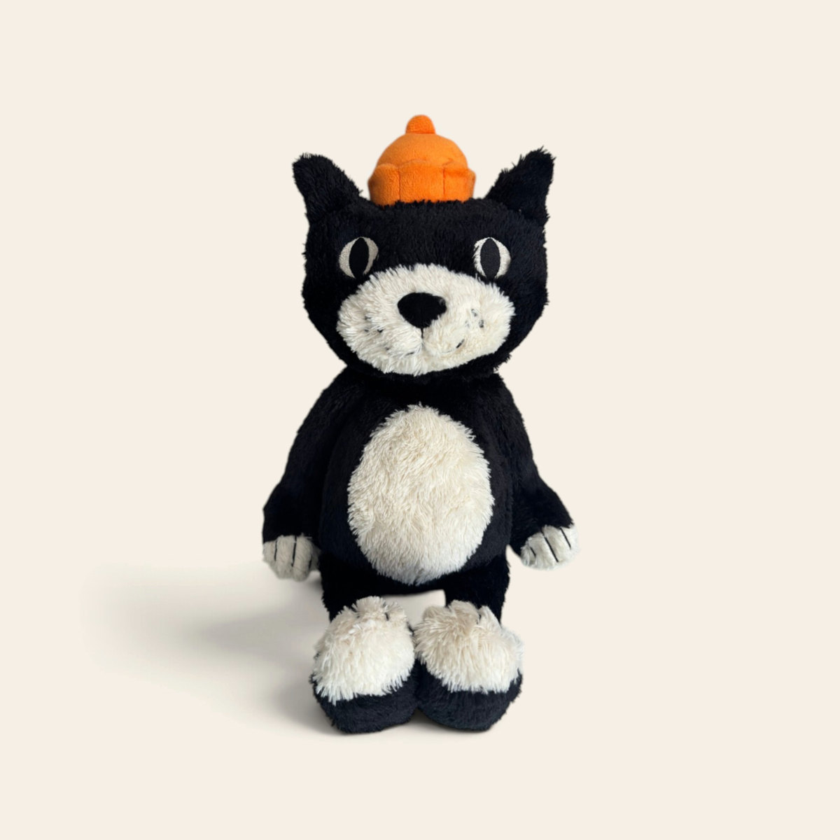Jellycat Jack JELC3M: a black and white plush cat with an orange bobble hat, sitting upright