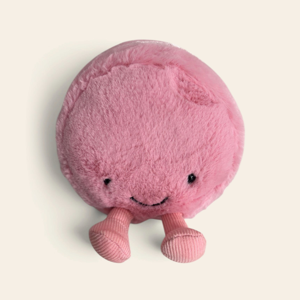 Amuseables Mia Macaron A6MACF: a round pink fluffy plush macaron toy with a smiling face and pink legs