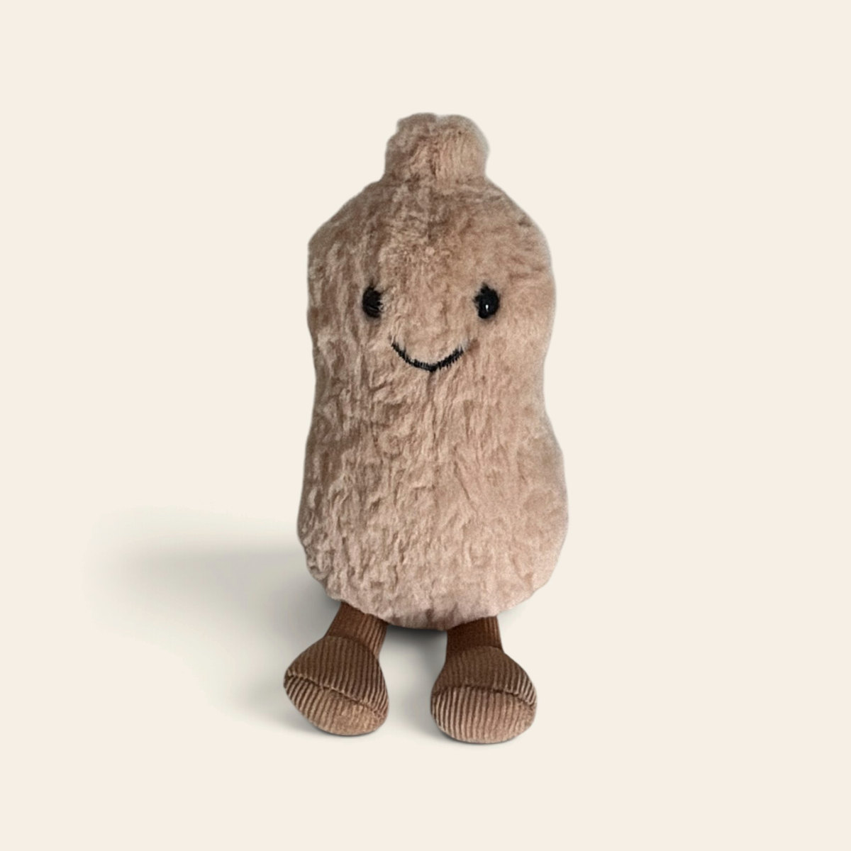 Amuseables Peanut A6PE: a beige fuzzy plush peanut toy with a smiling face and brown corduroy legs